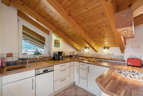 a kitchen with white cabinets and a wooden ceiling at Fewo Oberschönauer Bergblick in Schönau am Königssee