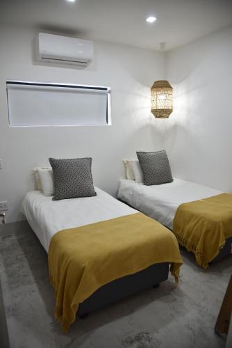 two beds in a room with white walls at Karoo Retreat- Self Catering Villas and Guest House in Oudtshoorn