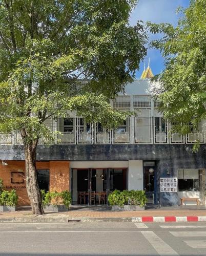 a building on the side of a street with a tree at Khunluang Hostel in Chiang Mai