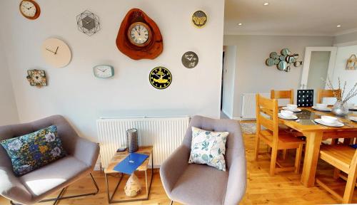 a living room with chairs and a table and clocks on the wall at Killiechangie House in Newtonmore