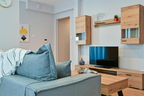 a living room with a blue couch and a tv at Elegant Sea View Stay - Piraeus Port in Piraeus