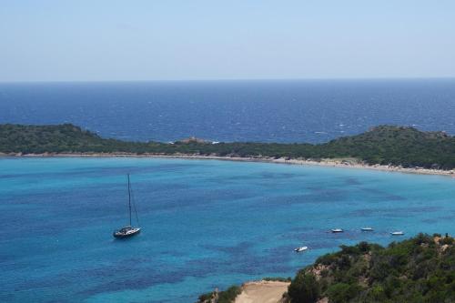 a sail boat in the water next to a beach at Capo Coda Cavallo, vacanze nella casa Il Maestrale in Capo Coda Cavallo