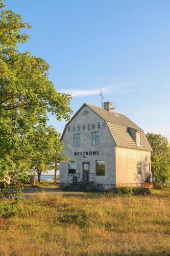 an old barn sitting in a field with a tree at Bungenäs Badhotell in Fårösund