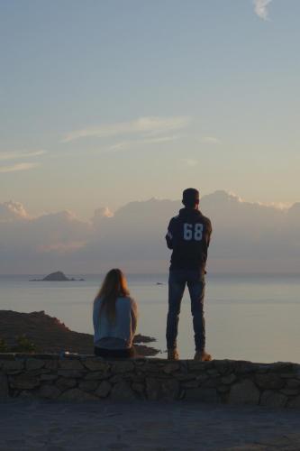 a man and a woman sitting on a wall looking at the ocean at Capo Coda Cavallo, vacanze nella casa Il Maestrale in Capo Coda Cavallo
