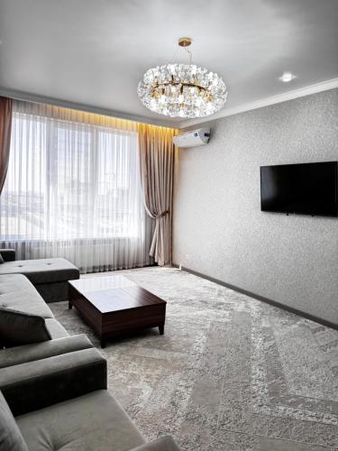 a living room with a couch and a flat screen tv at Посуточно 3 комн в ЖК Аль Фараби in Shymkent