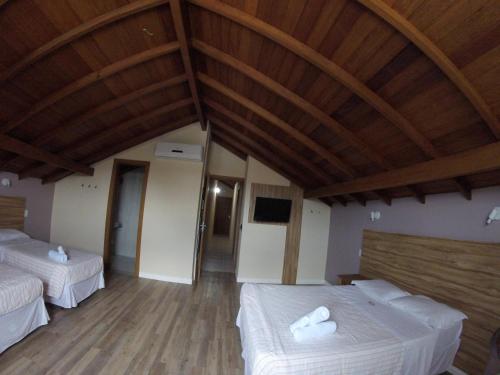 a bedroom with two beds and a wooden ceiling at Hotel Hola in Florianópolis