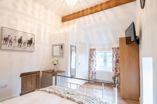 une chambre avec un lit et une télévision sur un mur dans l'établissement Lower House Farm Cottage 1, à Ashbourne