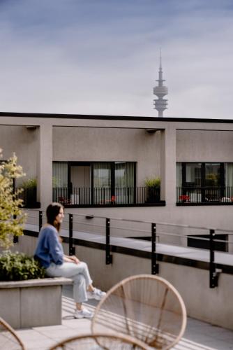 a woman sitting on a bench in front of a building at THE FLAG München M. in Munich