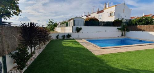 a backyard with a swimming pool and a green lawn at Vila T2 Algarve piscina privada in Vila Nova De Cacela