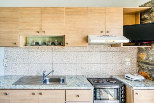 a kitchen with a sink and a stove and cabinets at Waves Melody in Kómi