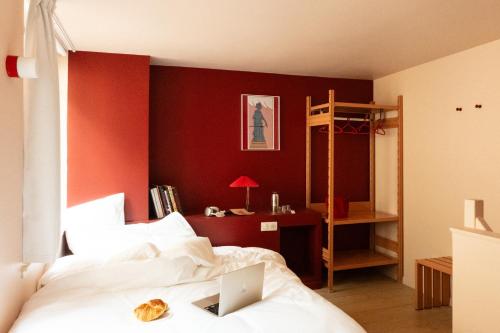 une chambre avec des murs rouges et un lit avec un ordinateur portable dans l'établissement Chez Georges - Auberge Contemporaine, à Lille