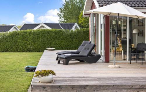 a chair and an umbrella on a wooden deck at Holiday Home Egernsund With A Fireplace 316 in Egernsund
