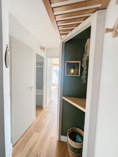 - un couloir avec un mur vert et du parquet dans l'établissement Appartement cosy, à Talmont-Saint-Hilaire