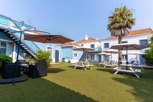 a patio with tables and umbrellas in front of a building at Mar- Milfontes Rentals in Vila Nova de Milfontes