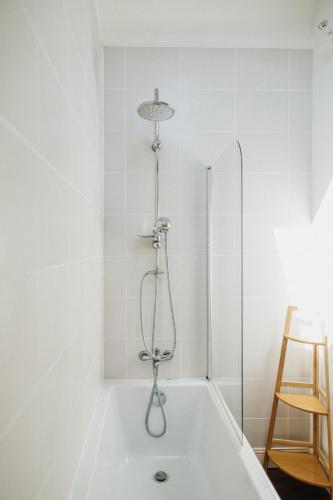 une baignoire blanche avec douche dans une salle de bain dans l'établissement La Petite Angele Cocon entre Terre et Mer, à Saint-Pierre-Église