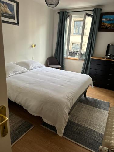 a bedroom with a large white bed and a window at Les 3 couronnes in Granville