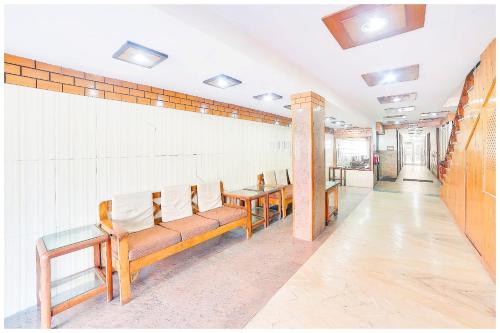 a waiting room with wooden benches and white chairs at HARIDWAR HOTEL HEAVEN # GUEST - With Free Parking & Wi-fi - Restaurant Facilities Available Near Temple - A Premium Hotel In Haridwar in Haridwār