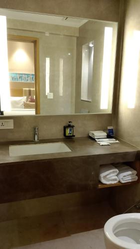 a bathroom with a sink and a toilet and a mirror at Sarovar Portico Rivera Ahmedabad in Ahmedabad