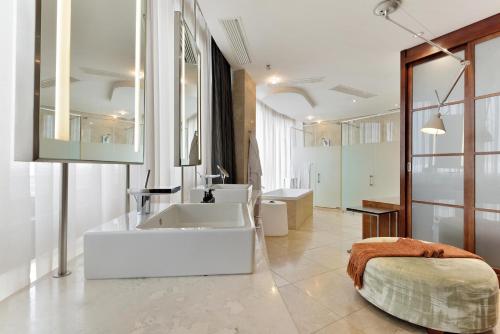 Un baño con una gran bañera blanca y un lavabo. en The Michelangelo Towers, en Johannesburgo