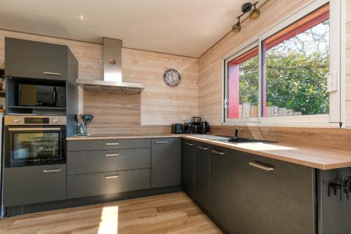 une cuisine avec des placards gris et une fenêtre dans l'établissement Gîte Le Champ Du Bois, à Missillac