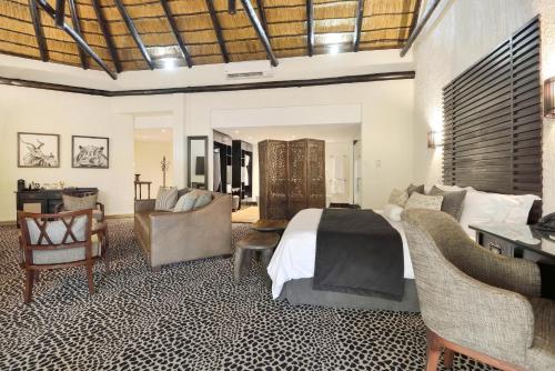 a bedroom with a bed and a couch and chairs at Bakubung Bush Lodge in Ledig