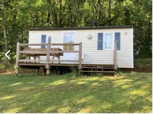 ein weißes, kleines Haus mit einer Veranda und einer Bank in der Unterkunft Camping 3 étoiles - Piscine - eehcdh in Soturac