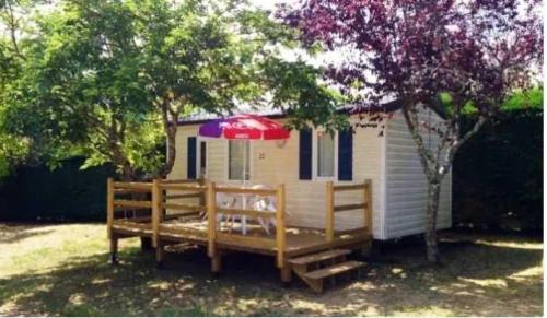 ein kleines Haus mit einer Terrasse und einem Sonnenschirm in der Unterkunft Camping 3 étoiles - Piscine - eehcdh in Soturac