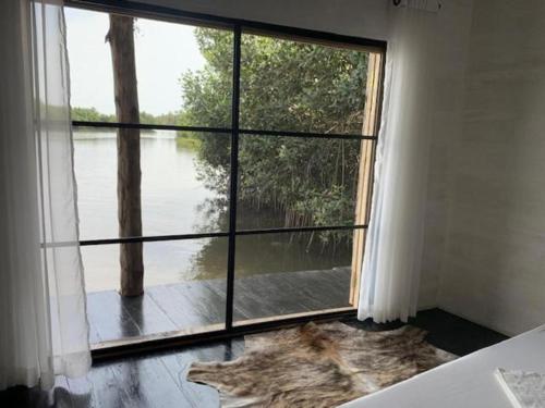 a room with a large window with a view of a river at Dolce Ouidah Lodge in Ouidah