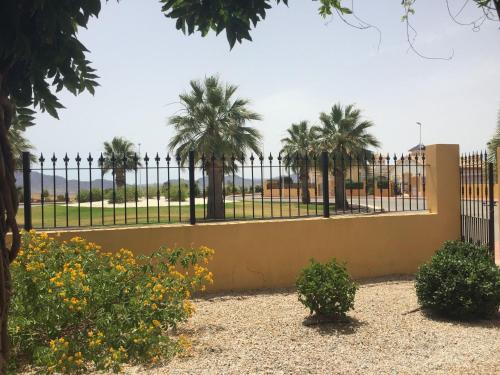 a fence with palm trees in the background at Casa Maravilla in Mazarrón