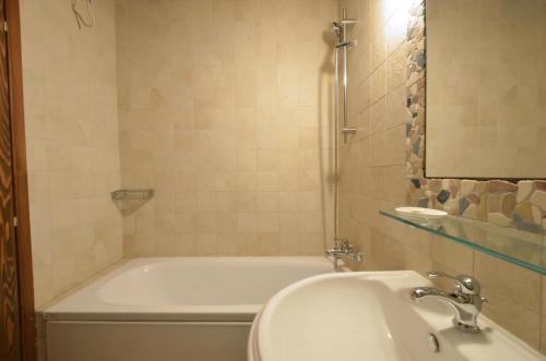 a bathroom with a tub and a sink and a mirror at Stone House Kotli in Kotli
