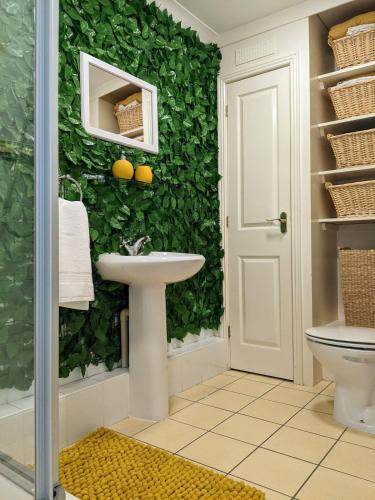 a bathroom with a green wall covered in ivy at Seaview Sands Beach Apartment in Southbourne
