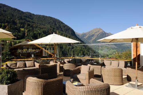 a patio with chairs and umbrellas with mountains in the background at Ruhige Wohnung Im Ortszentrum in Sankt Gallenkirch