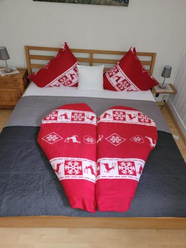 a bed with red and white blankets and pillows at Fewo Edelweiss in Nesselwängle