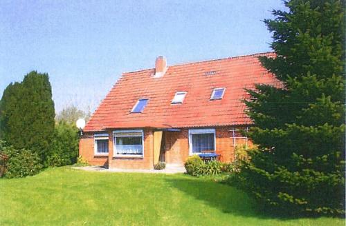 a house with a red roof on a green field at Ferienwohnung Ruheoase In Otterndorf in Otterndorf