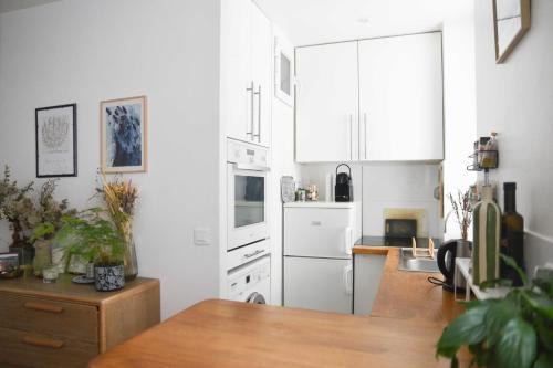 - une cuisine avec des appareils blancs et une table en bois dans l'établissement Bright 1 bedroom apartment - near park, à Paris