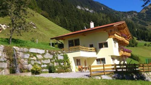 a house on a hill with a stone wall at Ferienwohnung In Brandberg Mit Garten in Mayrhofen