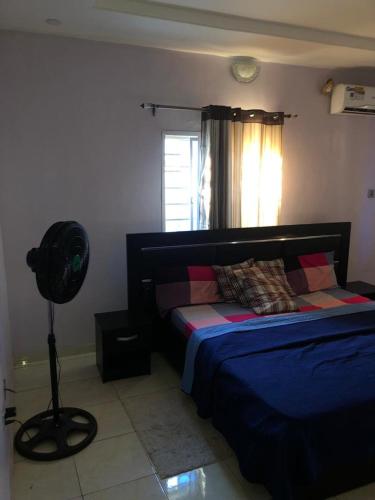 a bedroom with a bed and a fan next to a window at 3 Bedroom Bungalow at Heliu Estate in Enugu