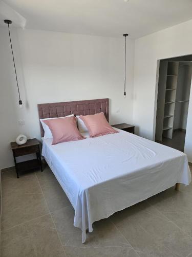 une chambre avec un grand lit blanc avec des oreillers roses dans l'établissement Villa neuve avec piscine, à Vauvert