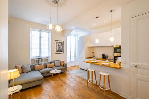 un salon avec un canapé et une cuisine dans l'établissement Apt 4 Guests Moderne & lumineux Paris 8ᵉ, à Paris