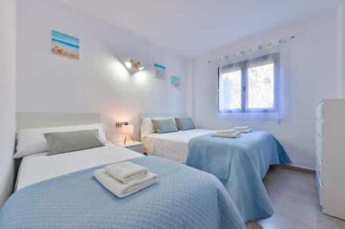 two beds in a white room with blue sheets at Villas Guzman - Paraiso Mar in Calpe