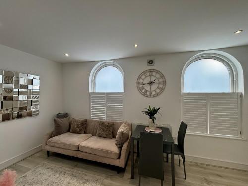 a living room with a couch and a table with a clock at Gogmore Lane in Chertsey