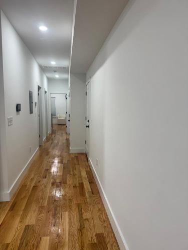 an empty hallway with white walls and wood floors at Cozy 3BR Retreat with Rooftop Near EWR & NYC Access in Newark