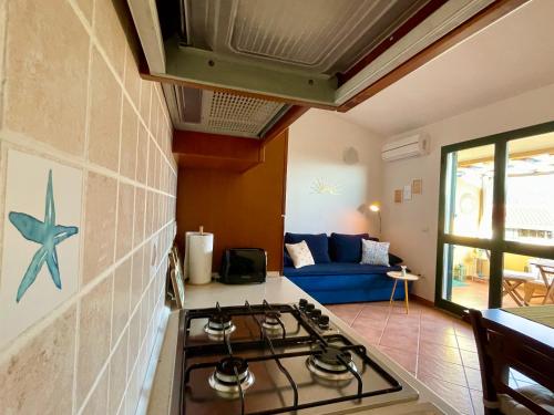 a kitchen with a stove and a blue couch at Appartamento Sunshine in Badesi