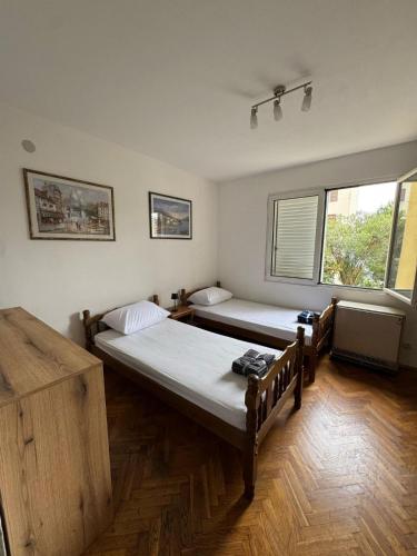 two beds in a room with two windows at Adriatic Escape Apartment in Herceg-Novi