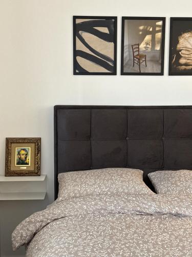 ein Bett mit schwarzem Kopfteil und vier Bildern an der Wand in der Unterkunft Sleep&Fly 1 Belgrade in Belgrad