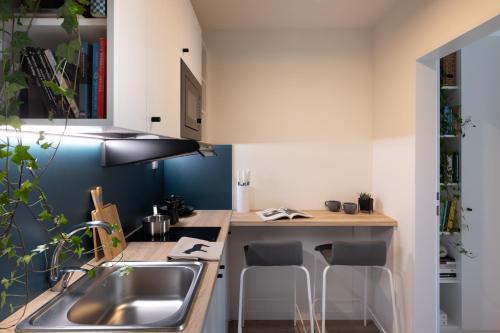une cuisine avec un évier et un comptoir avec des tabourets dans l'établissement MILESTONE Krakow Center Student Living, à Cracovie