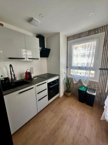 une cuisine avec des armoires blanches, un évier et une fenêtre dans l'établissement Chez LauLau, à Menton