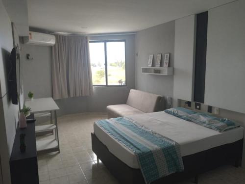 a bedroom with a bed and a couch and a window at Victory Flat Intermares in Cabedelo