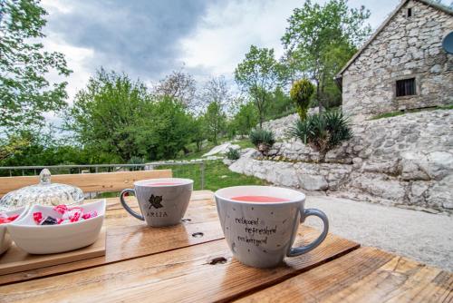 a wooden table with two coffee mugs on it at Arija Stone House - Rural Studio Apartment in Nikšić
