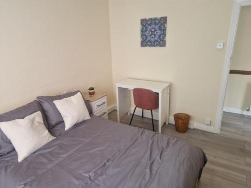 a bedroom with a bed with a chair and a desk at Arundel Road, RM30RX in Harold Wood